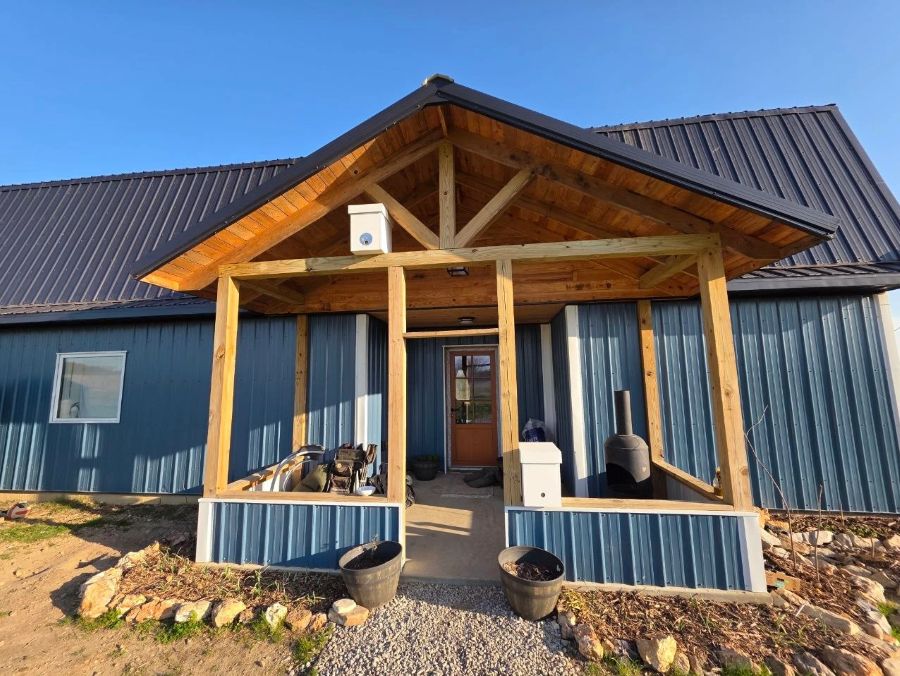 The blue barndominium's timber-framed front porch