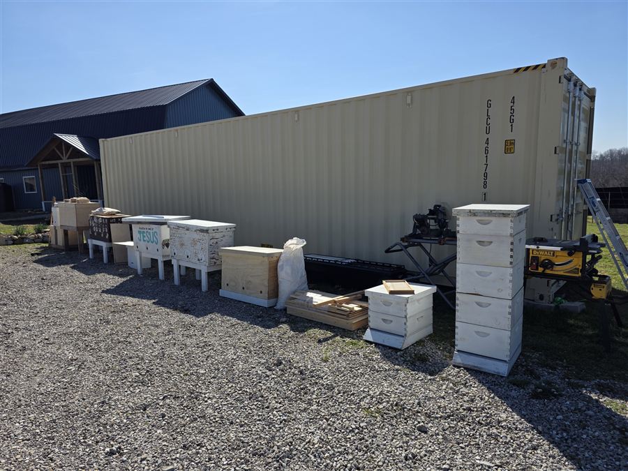 The 40ft high-cube container with hives lined along it, the blue barn behind