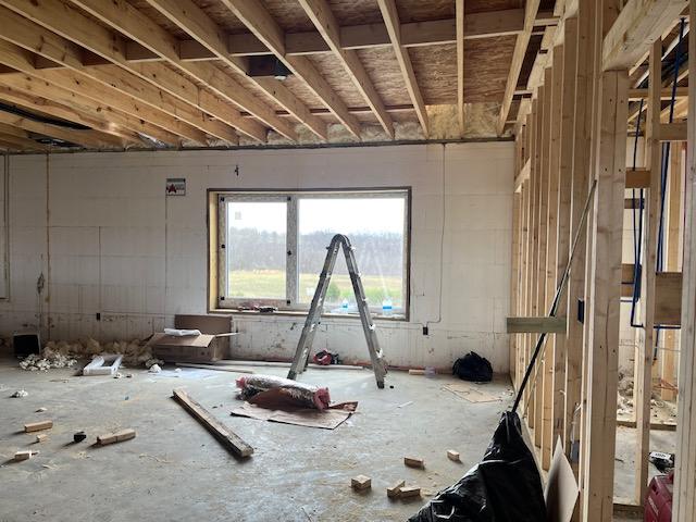 Unfinished interior room with a large window, exposed ICF walls and framing.