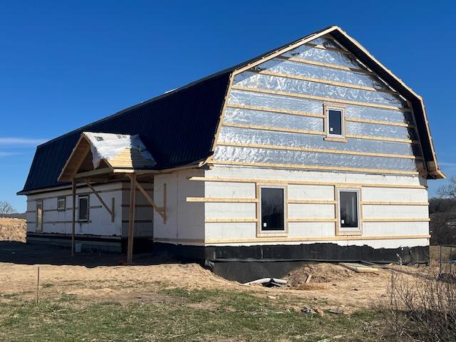 Exterior of the house with roof complete and insulation board still exposed on the walls.