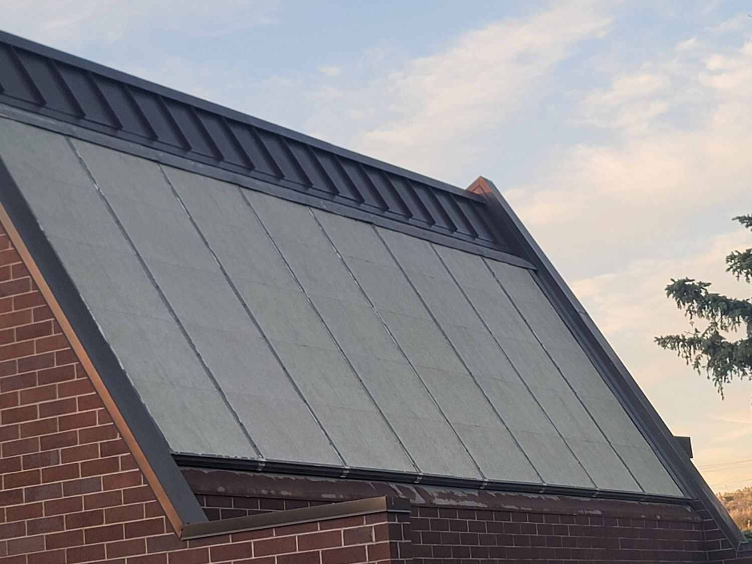 Close view of the steep south-facing roof covered in solar collector panels with clerestory venting along the ridge.